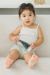 Baby girl sitting in Avauma floral tank set – white sleeveless top with sage green shorts
